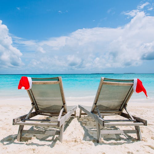 two sun loungers with christmas hats on a beach
