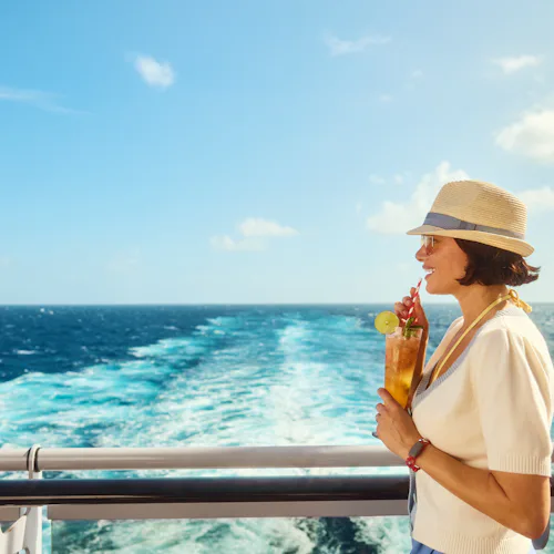 Woman with cocktail at aft of Virgin Voyages ship