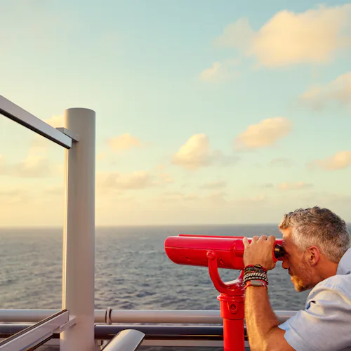 Man looking through telescope on Virgin Voyages ship